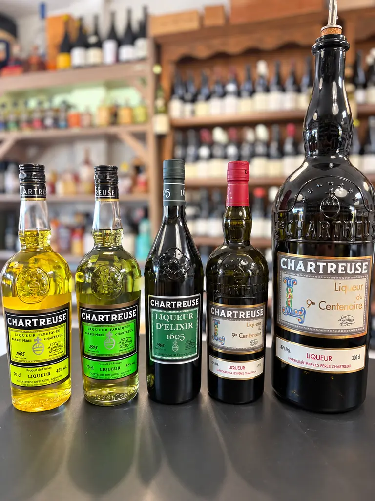 Collection de cinq bouteilles de liqueurs Chartreuse : Chartreuse jaune, Chartreuse verte, Liqueur d'Élixir 1605 et Chartreuse du 9e Centenaire en deux formats.